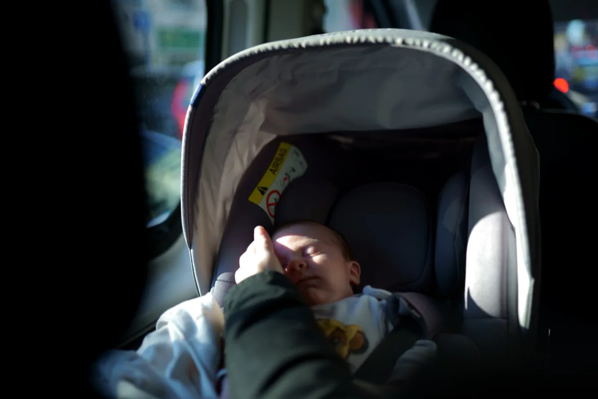Bebé en una sillita infantil dentro de un vehículo.