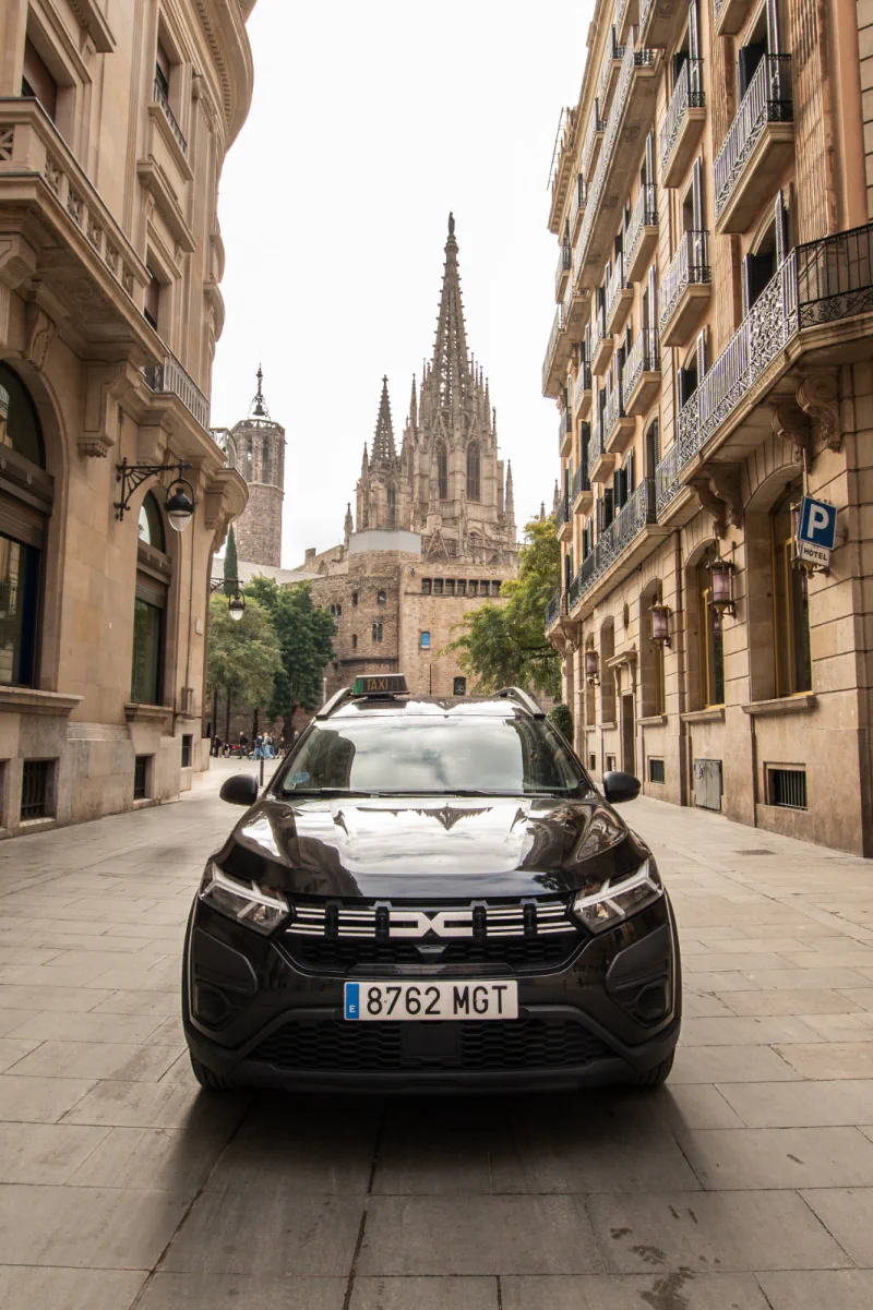 Taxi estacionado en una calle con la Catedral de Barcelona al fondo.